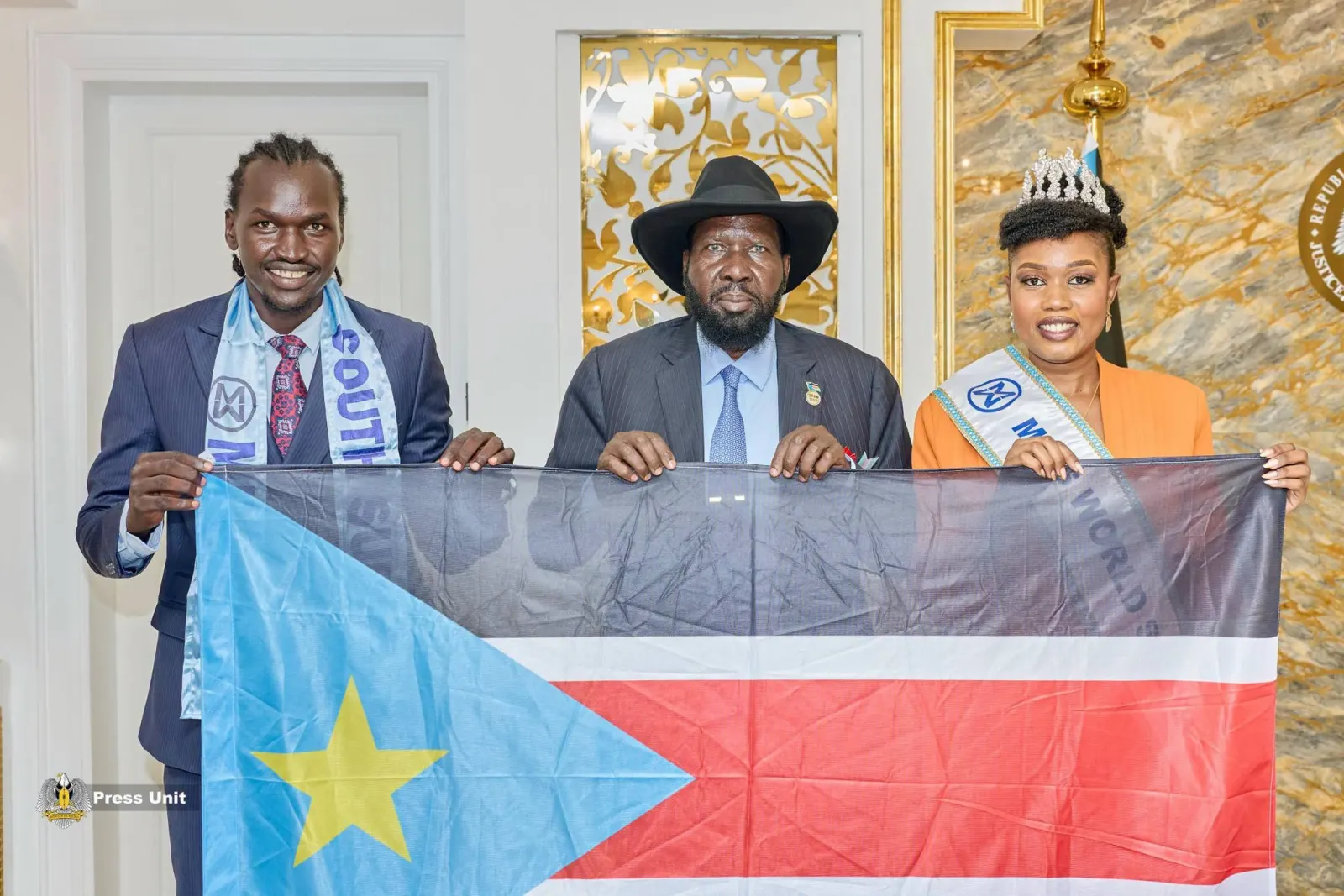President Salva Kiir, Miss World South Sudan 2026 Nyandeng Kerubino Kuanyin Bol, and Mr. World South Sudan Amac Mathiang Ater Apugi pose with the South Sudan national flag during a meeting at the Office of the President in Juba. Photo: Presidency Press Unit.